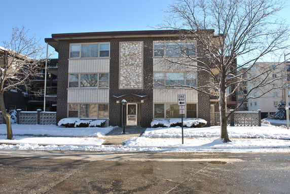 Front view of a three-story apartment building with a brick facade.