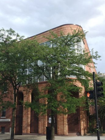 Front view of a multi-story building with large windows and a curved roof design.