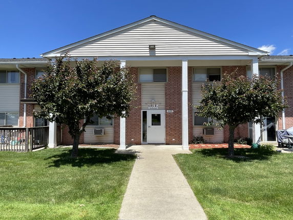 Front view of a two-story residential building with a brick facade and white columns.