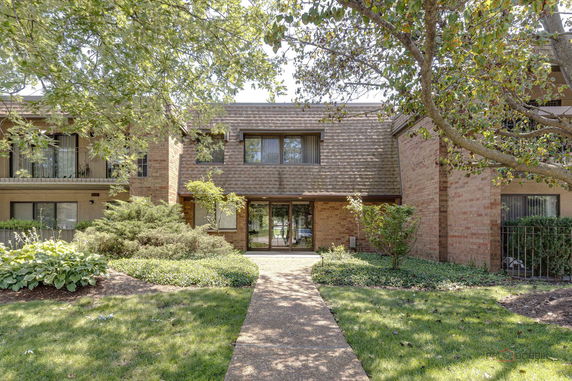Front view of a brick two-story building with a gabled roof and glass entrance.