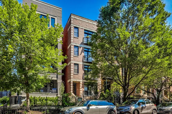 Front view of a multi-story residential building with brick facade and balconies.
