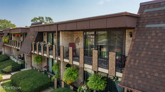 Front view of a multi-story building with balconies and a brown shingled roof.