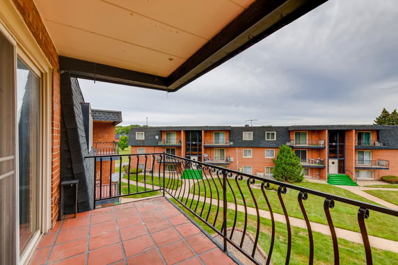 View from a balcony overlooking residential buildings and green space.