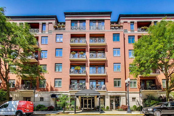 Front view of a multi-story brick apartment building with balconies.