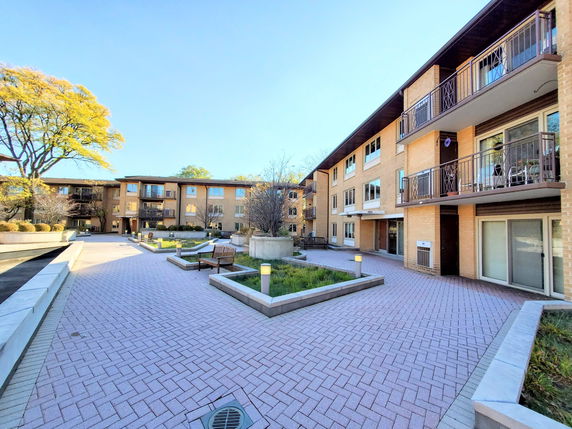 Front view of a multi-story residential building with balconies and a courtyard.