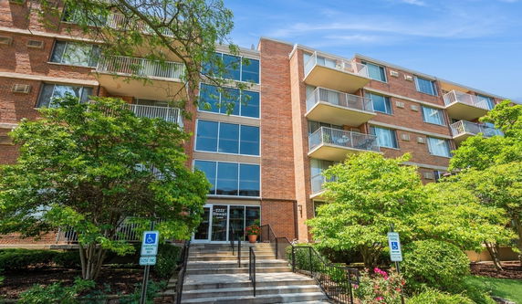 Front view of a multi-story brick apartment building with balconies and large windows.