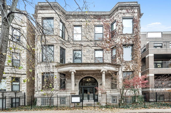 Front view of a multi-story stone building with arched entrance and columns.