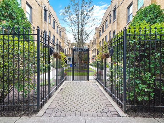 Front view of a multi-story residential building with a gated entrance.