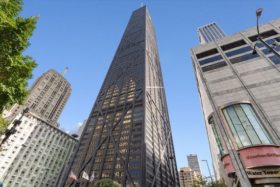 Front view of a tall skyscraper with distinctive diagonal braces in an urban setting.