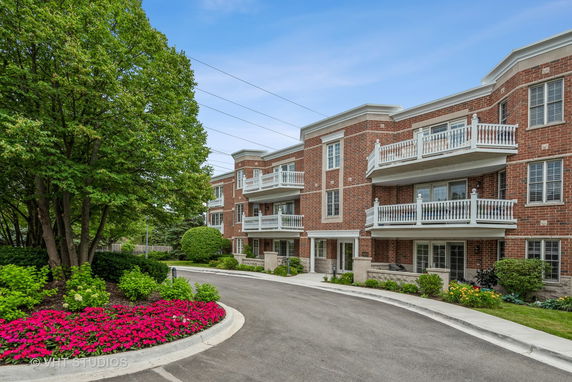 Front view of a multi-story brick building with white railings and balconies.
