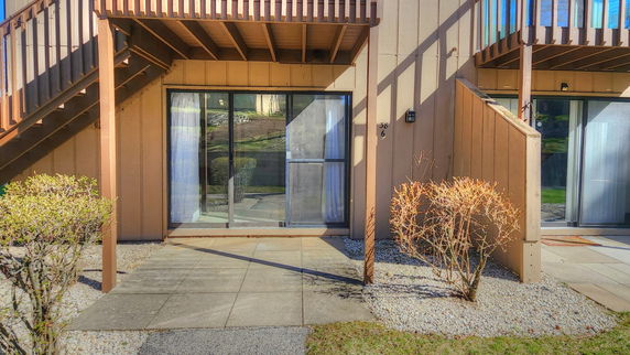 Front view of a multi-story building with sliding glass doors and external wooden staircase.