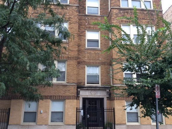 Front view of a multi-story brick building with several windows.