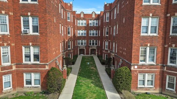 Front view of a red brick multi-story apartment building with a courtyard.