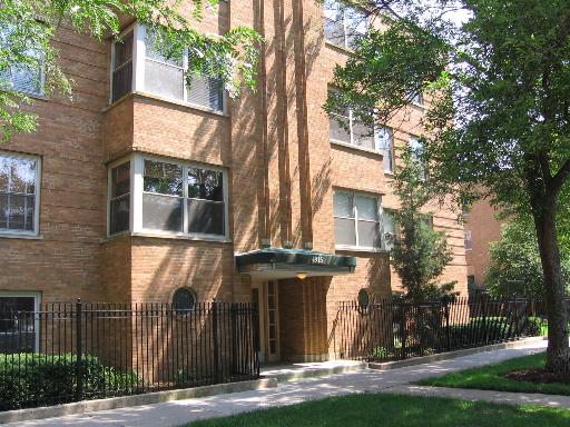 Front view of a multi-story brick apartment building with a small entrance porch.