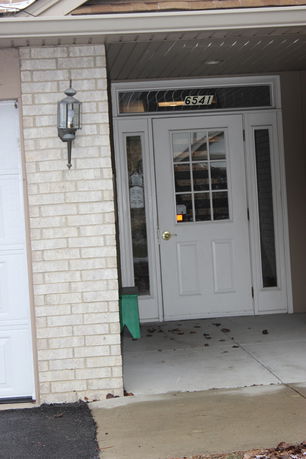 Front view of a house entrance with a white door and brick exterior.