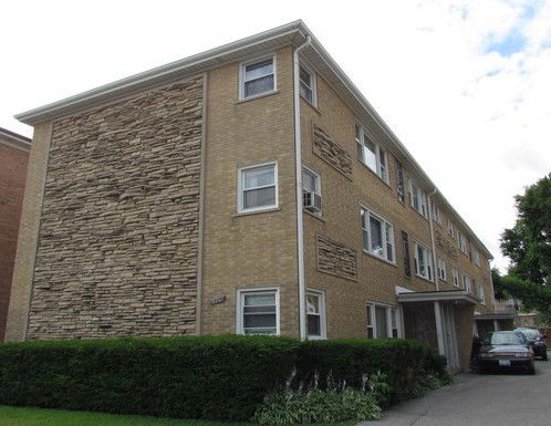 Front view of a three-story apartment building with a brick facade and stone accents.