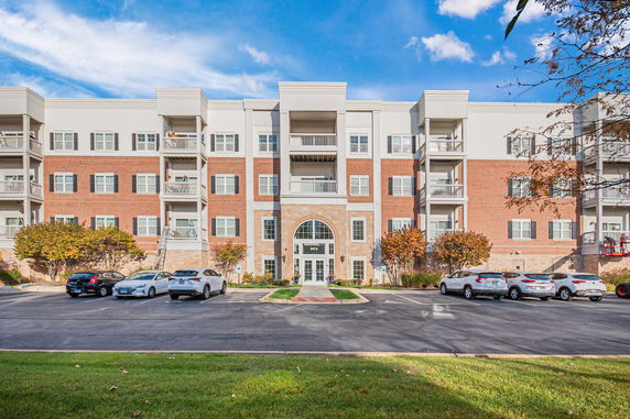 Front view of a multi-story residential building with balconies and a parking area.