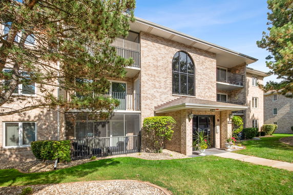 Front view of a multi-story brick apartment building with balconies.