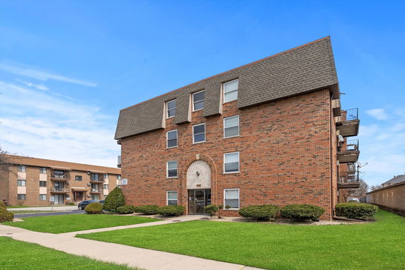 Front view of a brick apartment building with multiple floors and balconies.