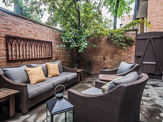 Outdoor seating area with wicker furniture and brick walls.