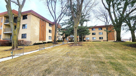 Front view of a multi-story apartment building with trees in the foreground.