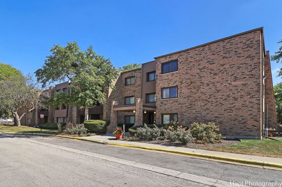 Front view of a multi-story brick apartment building with entrance.