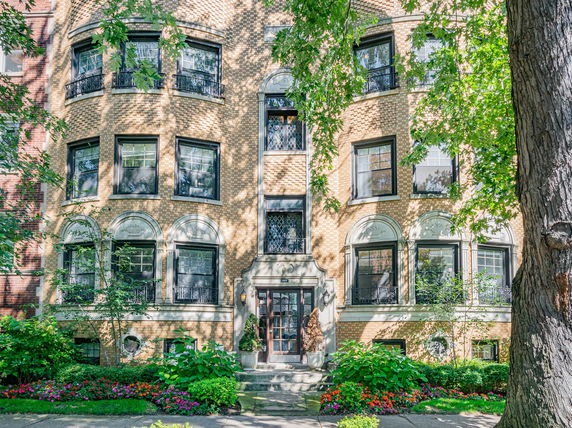 Front view of a multi-story apartment building with a brick facade and multiple windows.
