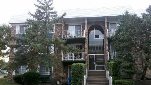 Front view of a brick residential building with balconies and a central entrance.
