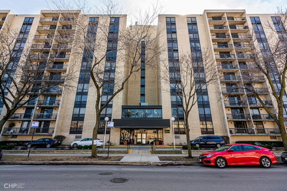 Front view of a multi-story apartment building with balconies and large windows.