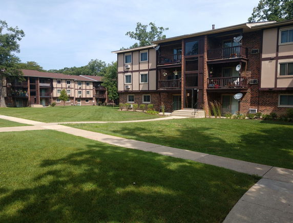 Front view of a multi-story apartment building with balconies and brick facade.