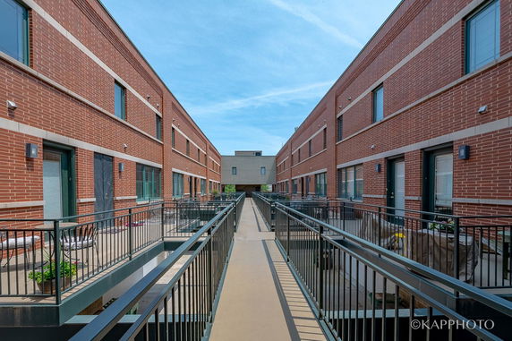 Front view of a red brick building with multiple entrances and a walkway.