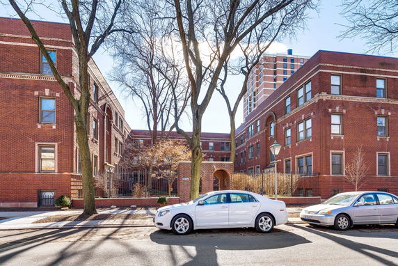 Front view of a multi-story red brick building with large windows and an arched entrance.