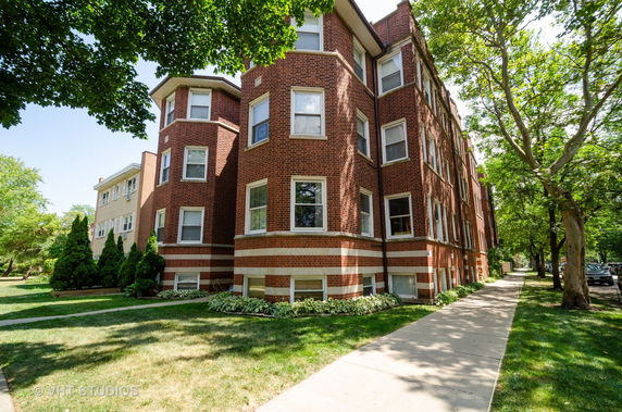 Front view of a multi-story brick apartment building with bay windows.