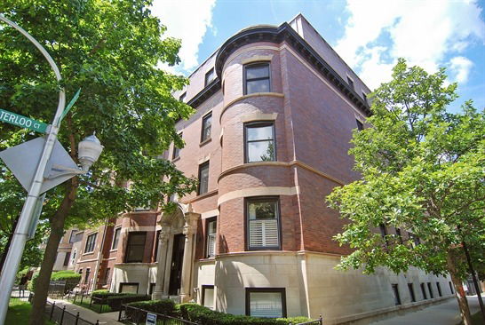 Front view of a multi-story brick building with rounded corner sections and multiple windows.