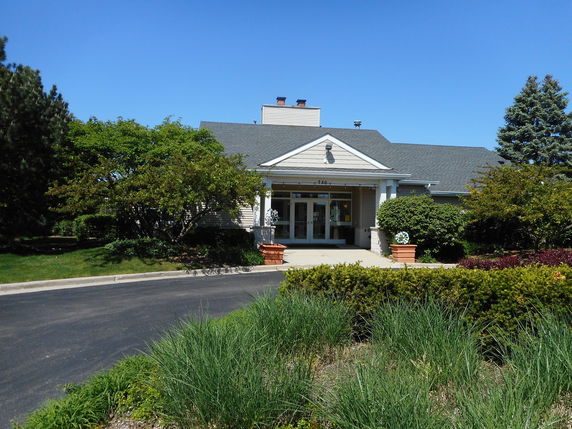 Front view of a single-story house with a porch and shrubs in front.