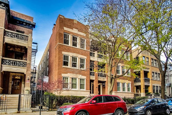 Front view of a multi-story brick apartment building with balconies.