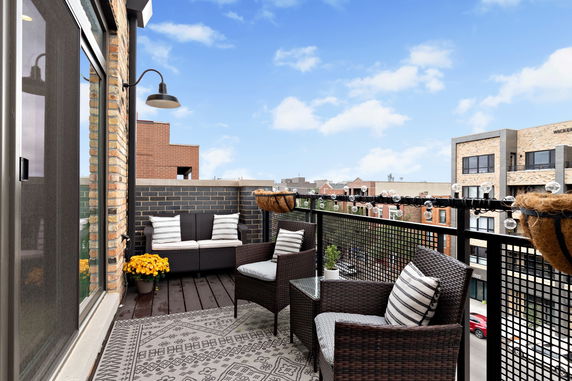 Rooftop patio area with wicker furniture and decorative lighting.