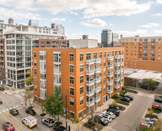 Elevated view of a multi-story apartment building with orange brick facade and balconies.