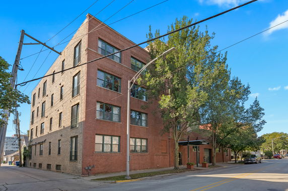 Front view of a multi-story brick building on a street corner.