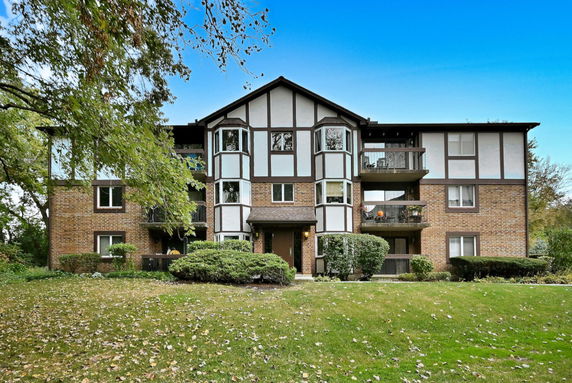 Front view of a three-story apartment building with brick and wooden paneling.