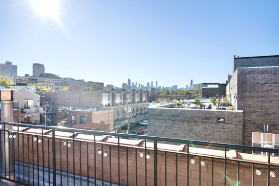 Wide angle view of surrounding buildings from a rooftop with city skyline in the background.