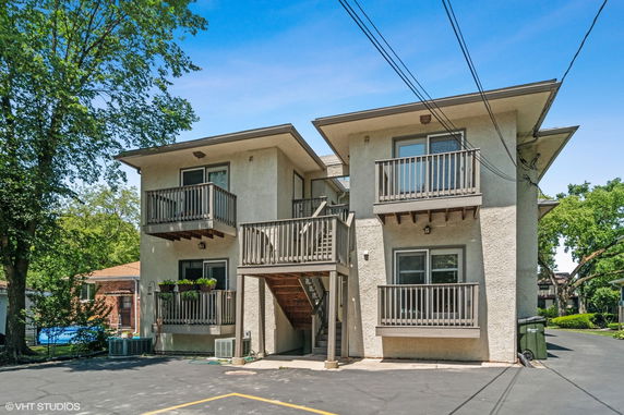 Front view of a two-story building with balconies and an external staircase.