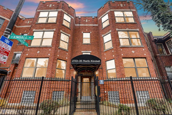 Front view of a brick apartment building with multiple large windows.