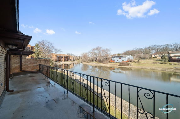 Balcony view overlooking a body of water and residential buildings in the background.