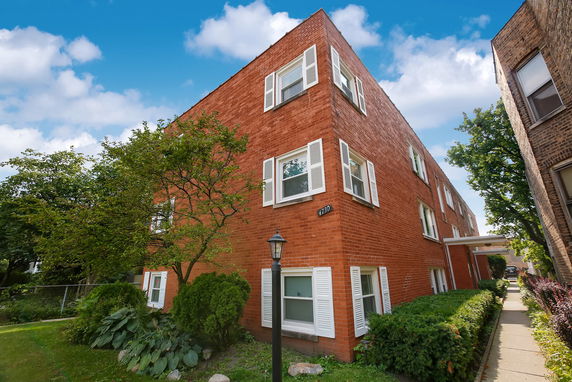 Front view of a two-story brick building with white window shutters.