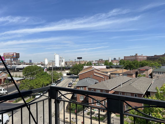 Wide angle view of rooftops and distant industrial buildings from a balcony.