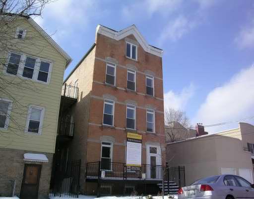 Front view of a three-story brick building with a triangular roof detail.