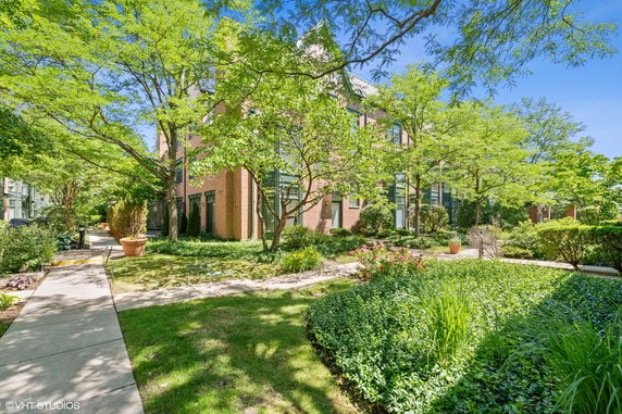Front view of a multi-story brick building surrounded by trees and greenery.