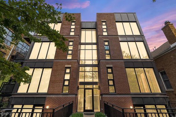 Front view of a multi-story building with large windows and brick exterior.