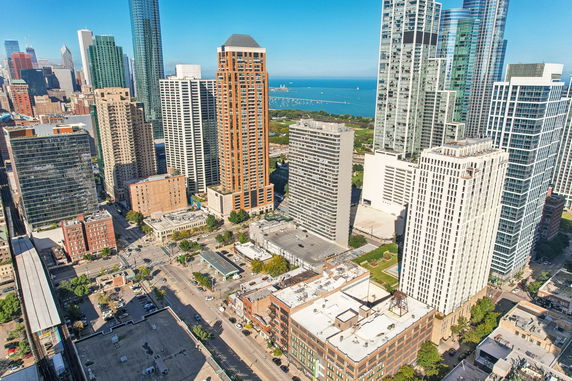 Panoramic view of a cityscape with tall buildings and a body of water in the background.